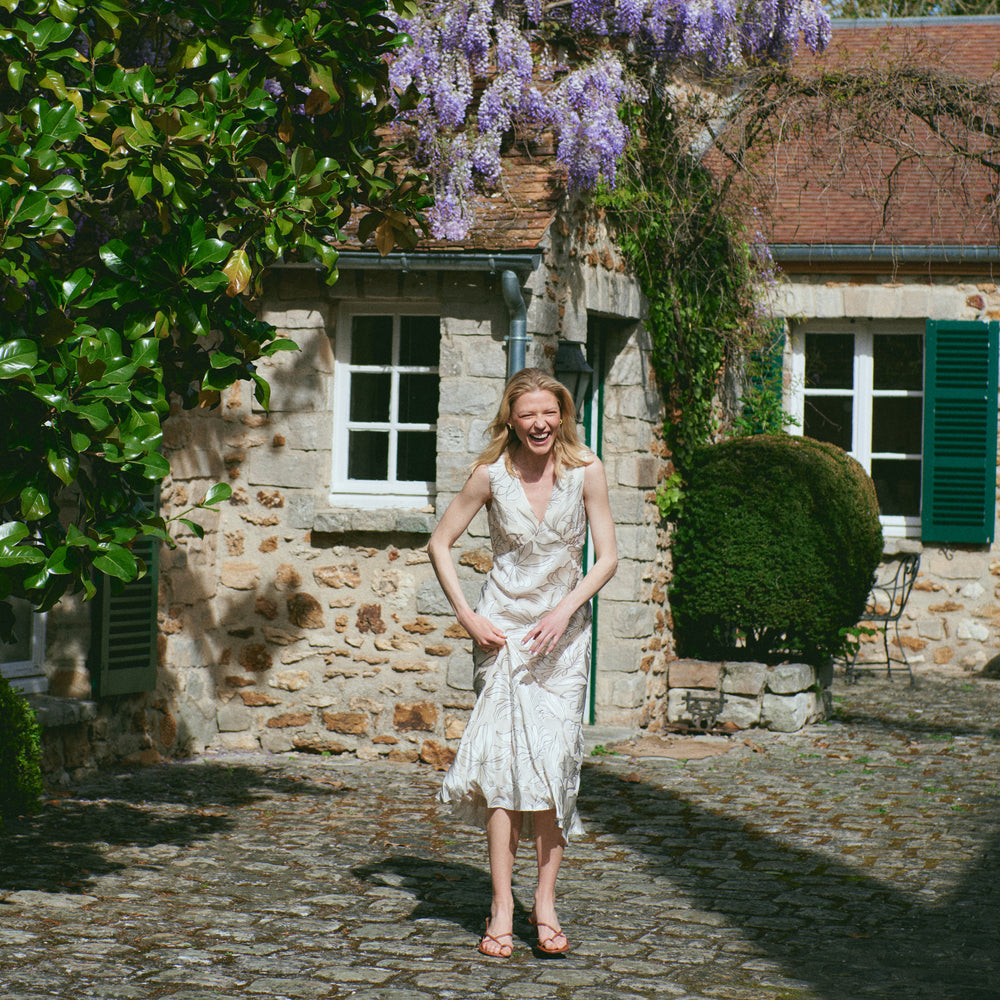 Woman in a white dress standing in front of a stone building with wisteria