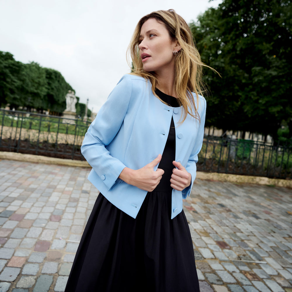 Woman wearing a blue blazer over a black dress in the city