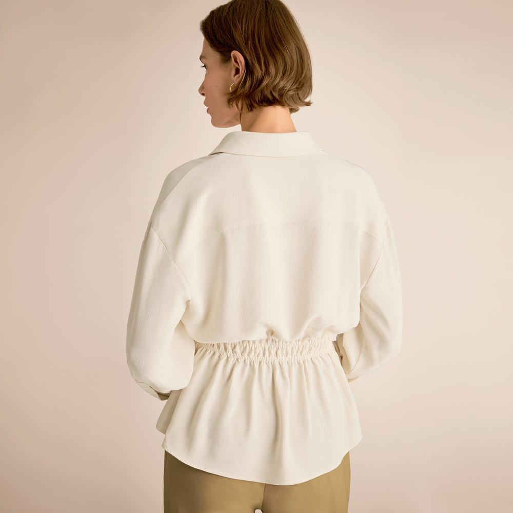 Woman wearing a white blouse against a beige background