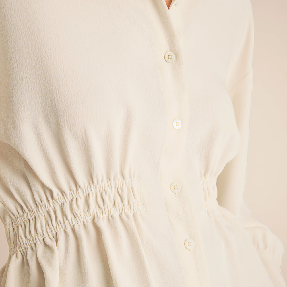 Close-up of a beige dress with button details on a light background