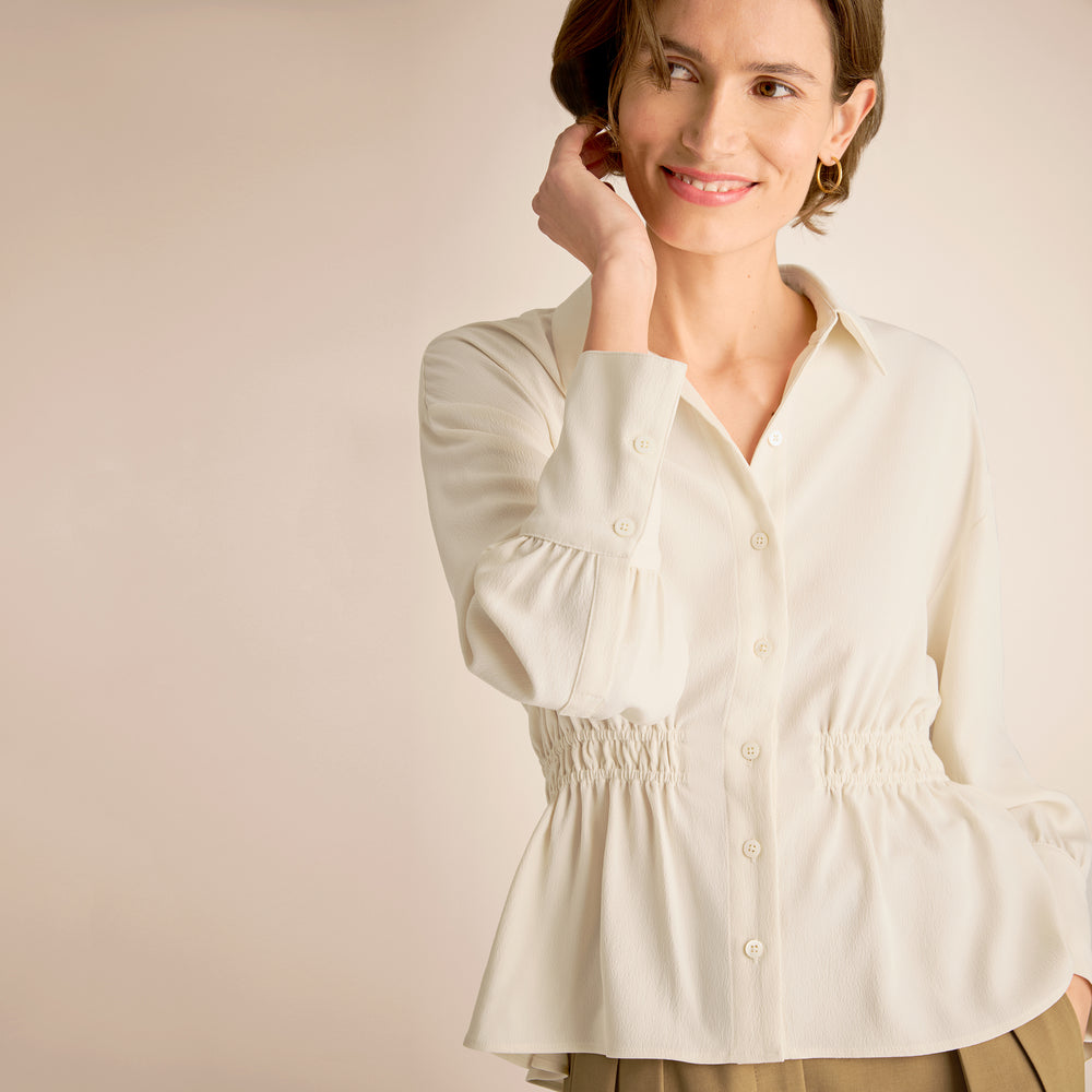Woman wearing a white blouse against a beige background
