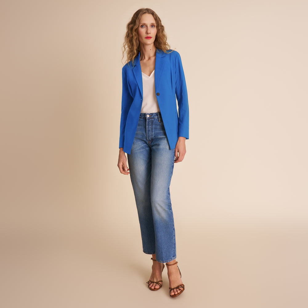 Woman wearing a blue blazer and jeans on a beige background