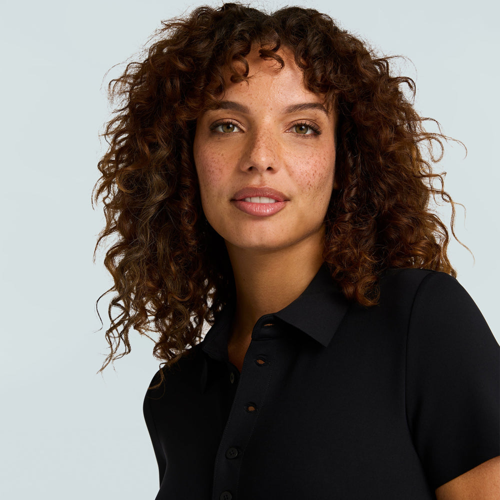 Woman wearing a black bodysuit against a light gray background