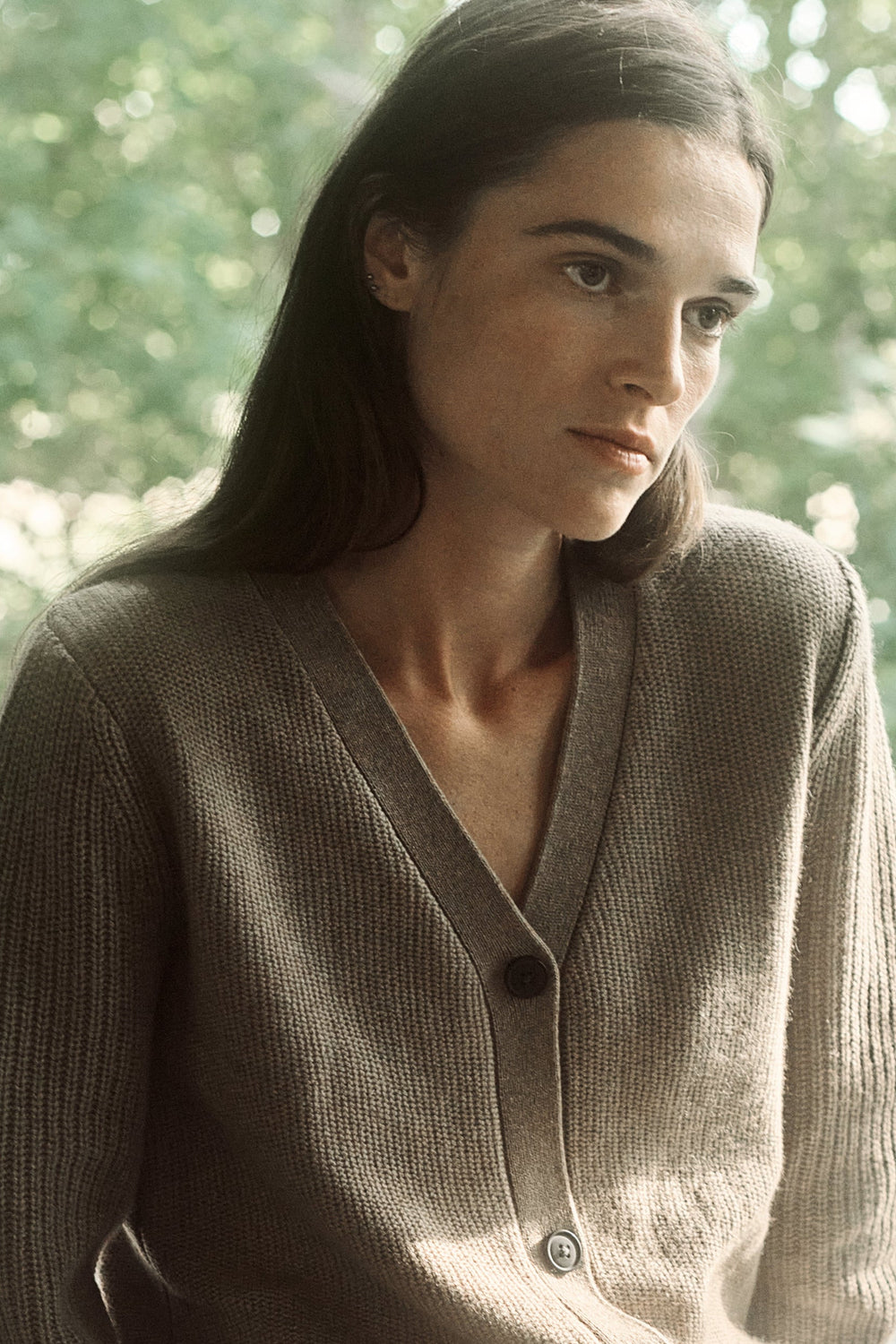 Woman wearing a beige cardigan standing in a forest