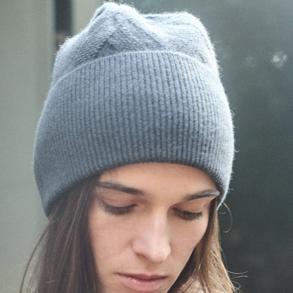 Woman wearing a gray knit beanie with a blurred background