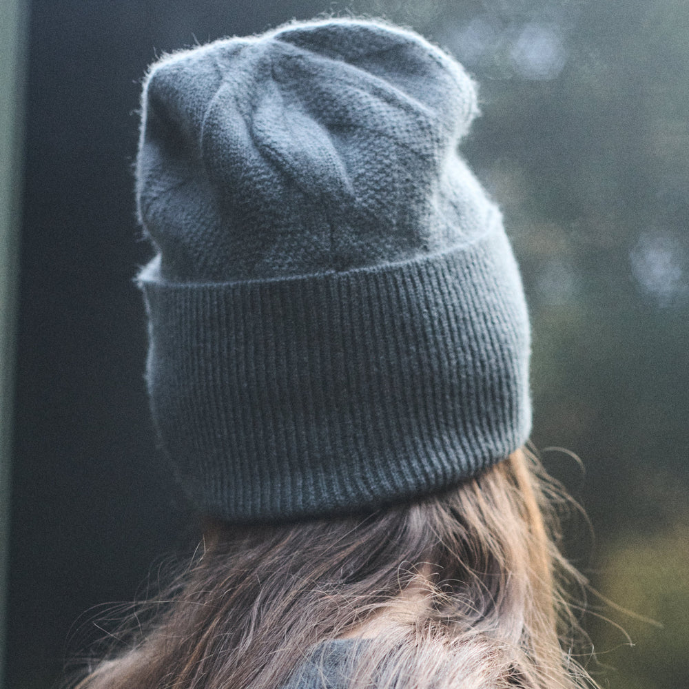 Person wearing a blue knit beanie with blurred background