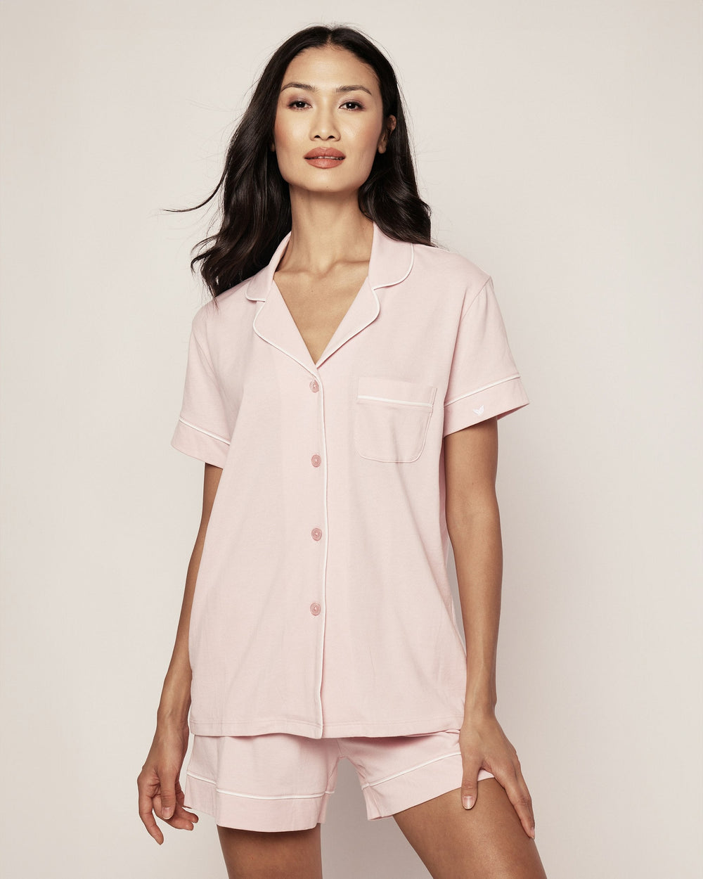Woman wearing a pink pajama set against a plain background
