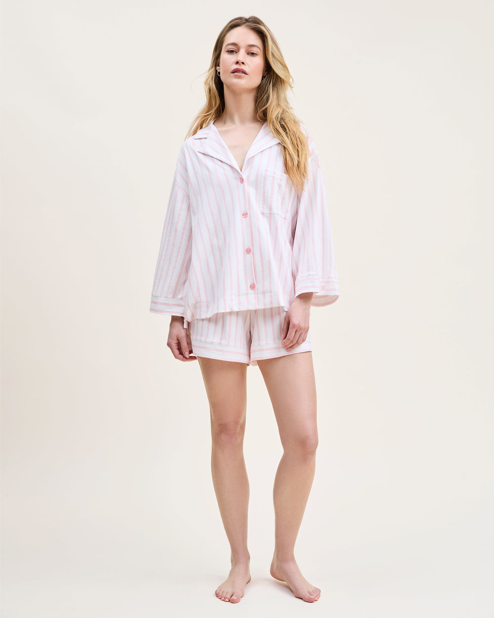 Woman wearing a light pink pajama set on a white background
