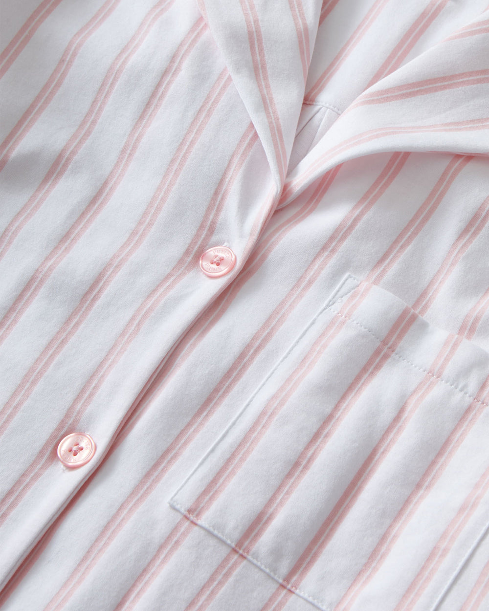 Close-up of a white shirt with pink vertical stripes and buttons.