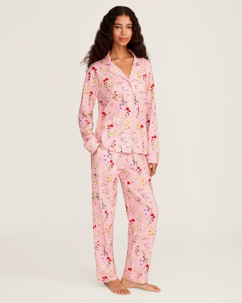 Woman wearing a pink floral pajama set on a white background