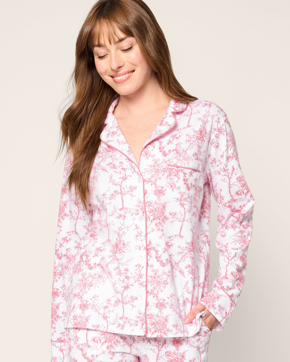 Woman wearing a pink floral pajama set against a plain background