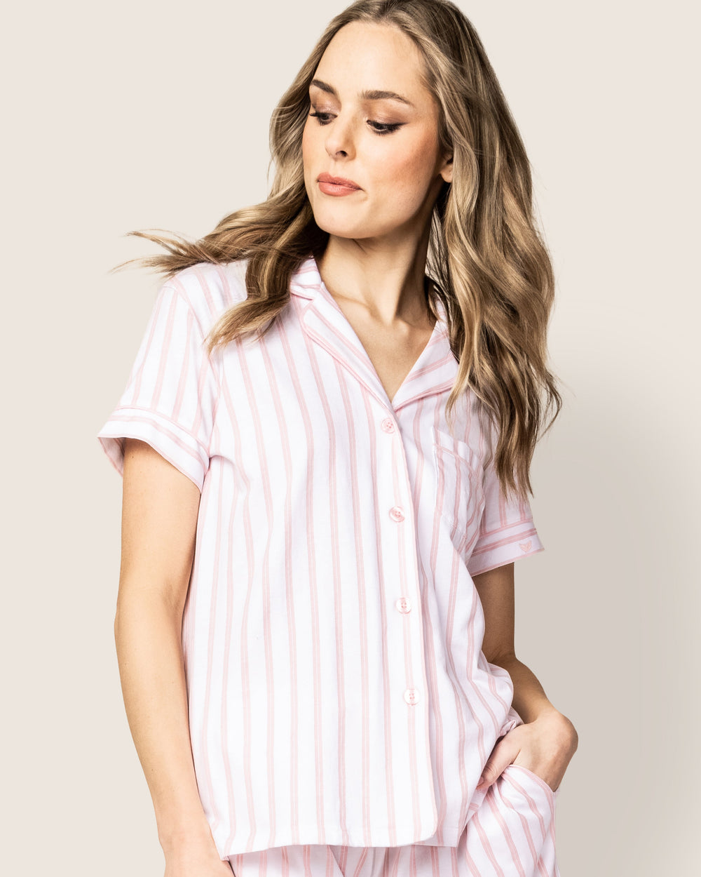 Woman wearing a pink striped shirt against a plain background