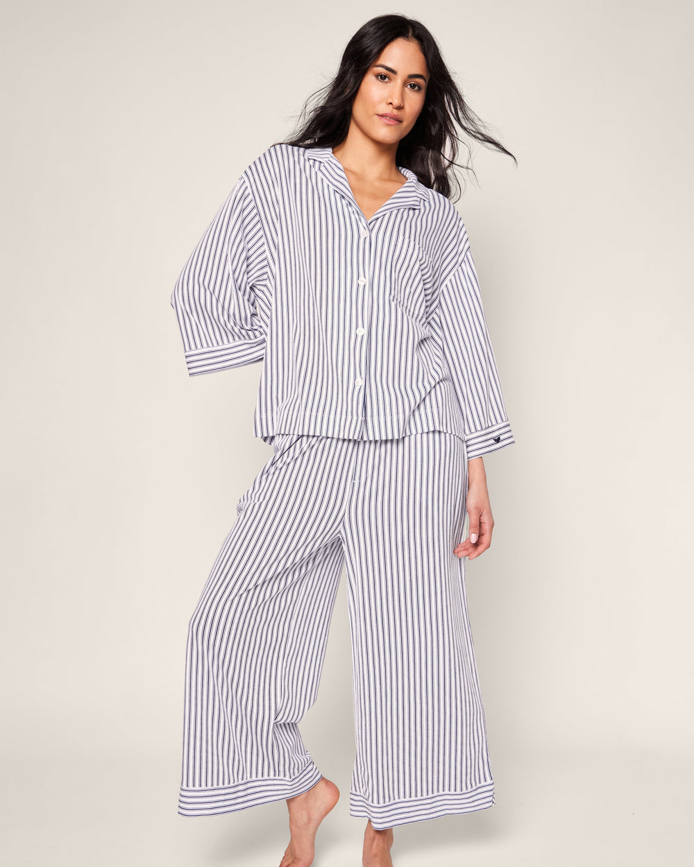 Woman wearing a striped pajama set on a plain background