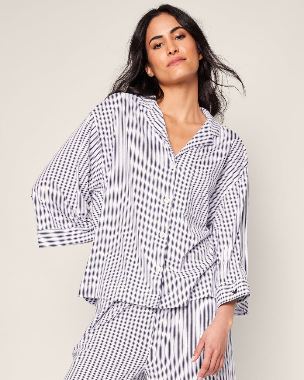 Woman wearing a striped pajama set against a plain background