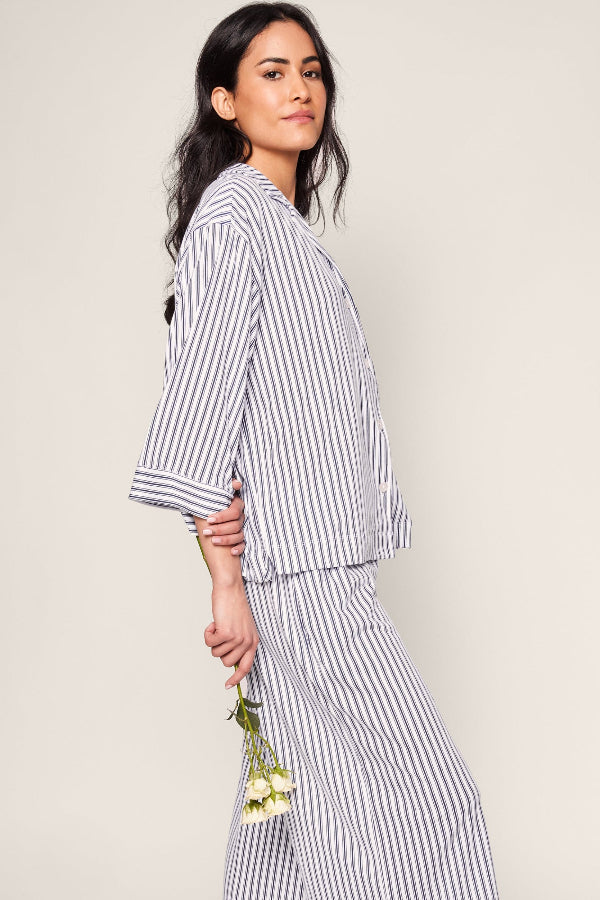 Woman wearing a striped outfit holding flowers against a plain background