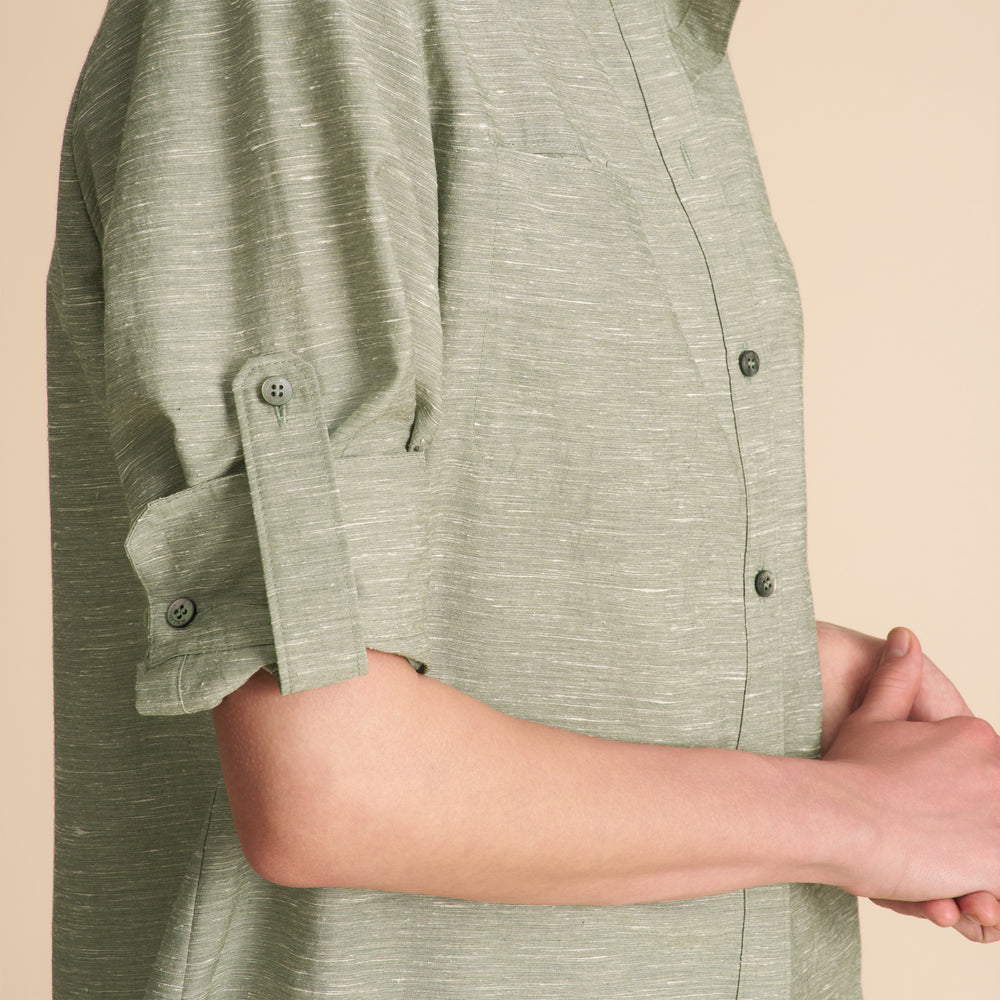 Person wearing a green textured shirt with button details on a beige background