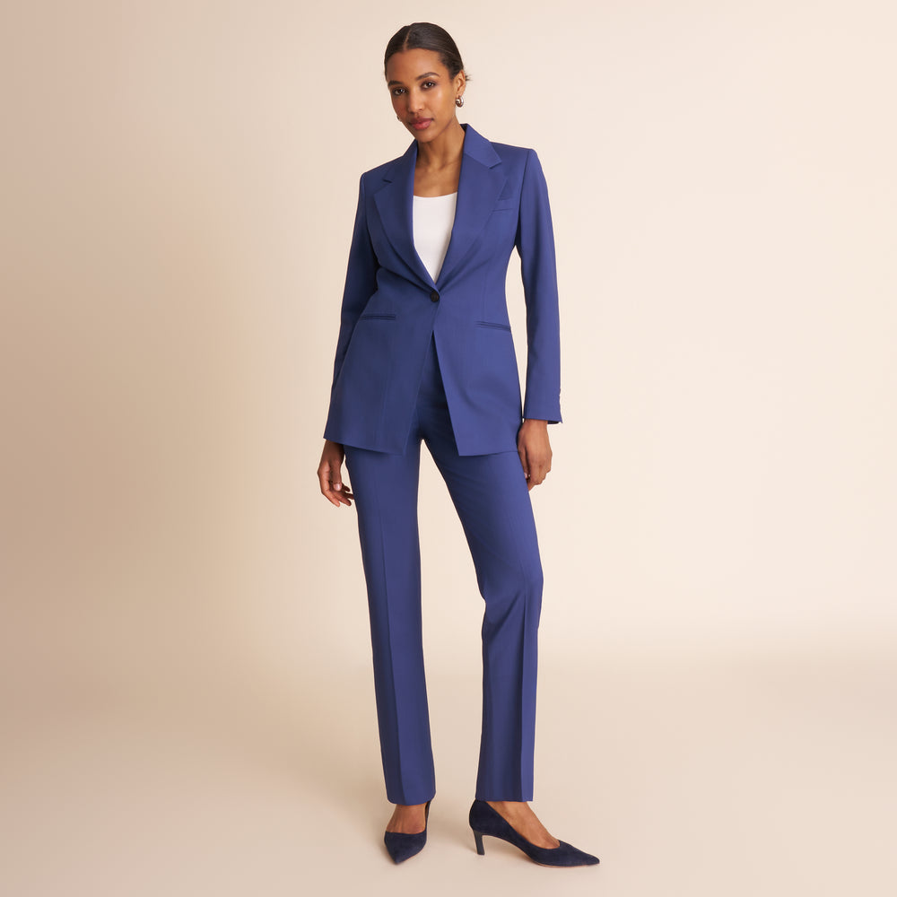 Woman wearing a blue suit with a white top on a beige background.