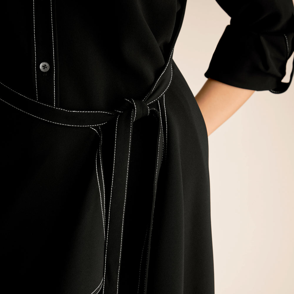 Close-up of a black dress with a tie waist on a beige background