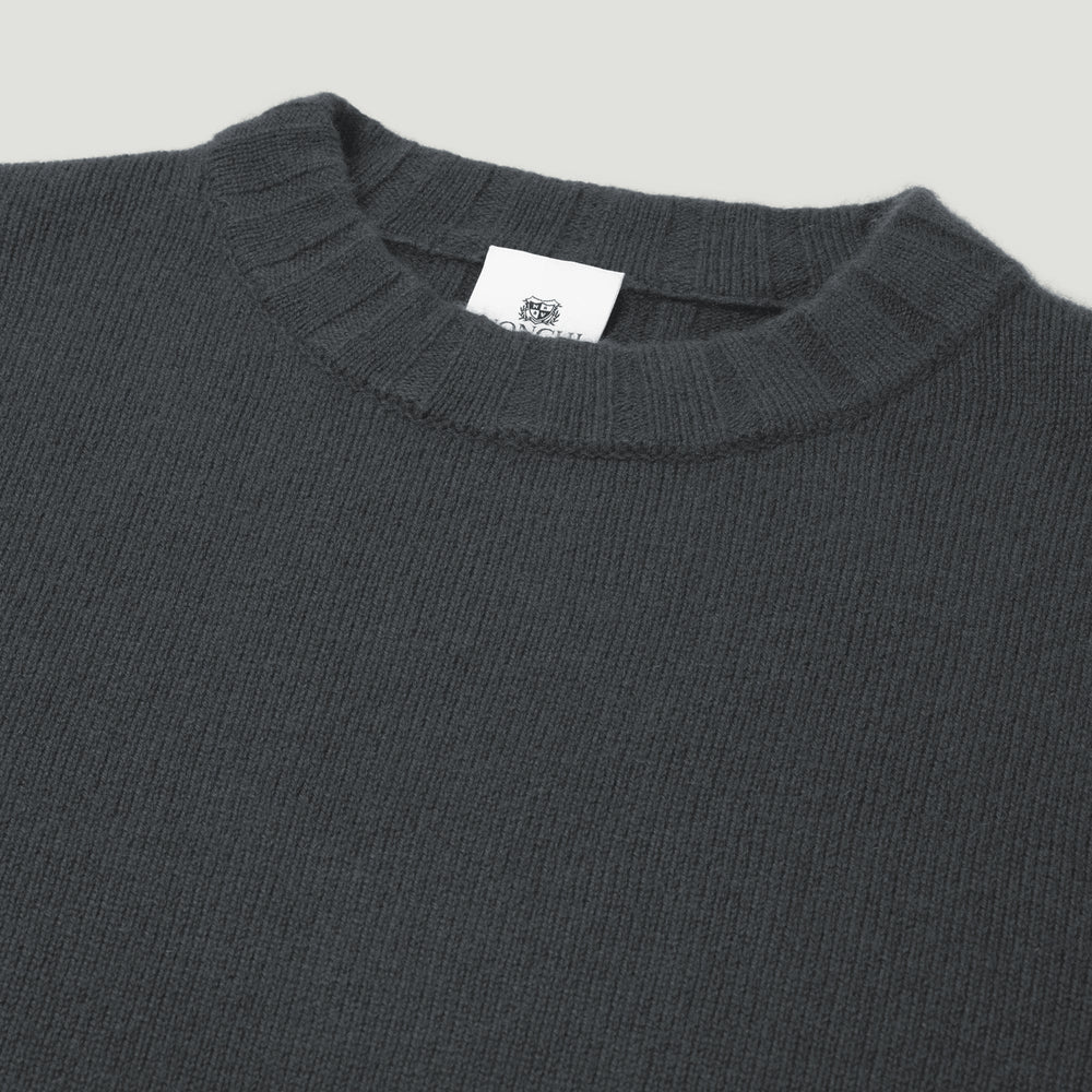 Dark gray sweater with a brand label on a light gray background