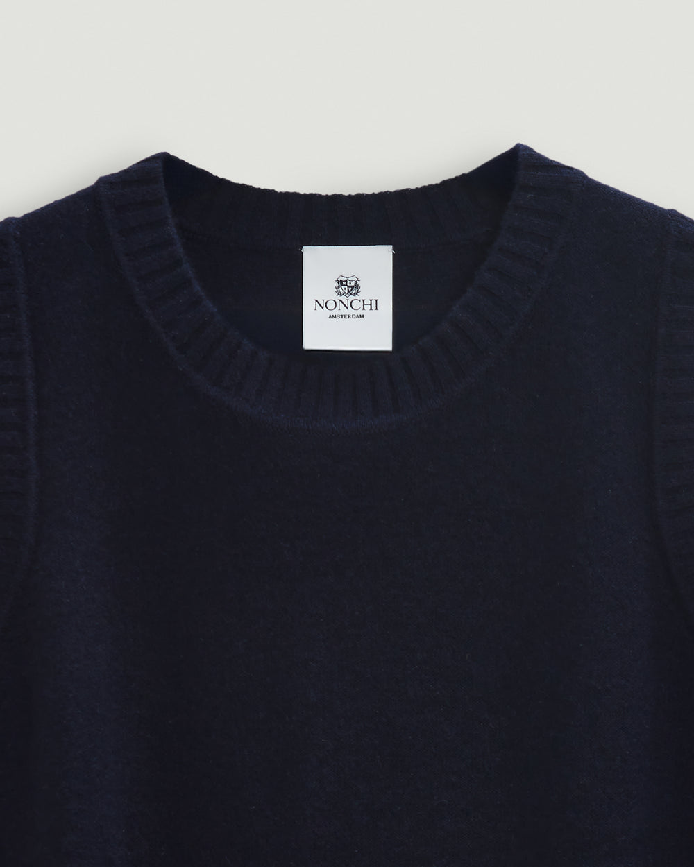 Navy sweater with a Nonchi label on a light gray background
