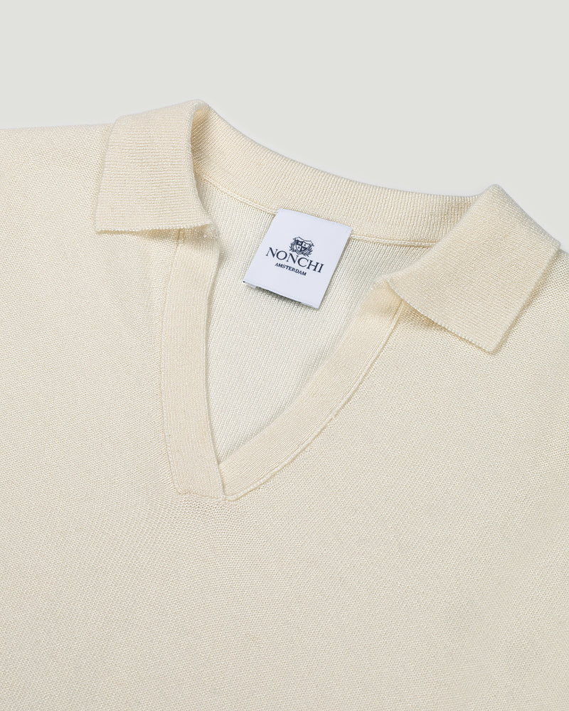 Close-up of a cream-colored sweater with a Nonchi label on a light gray background