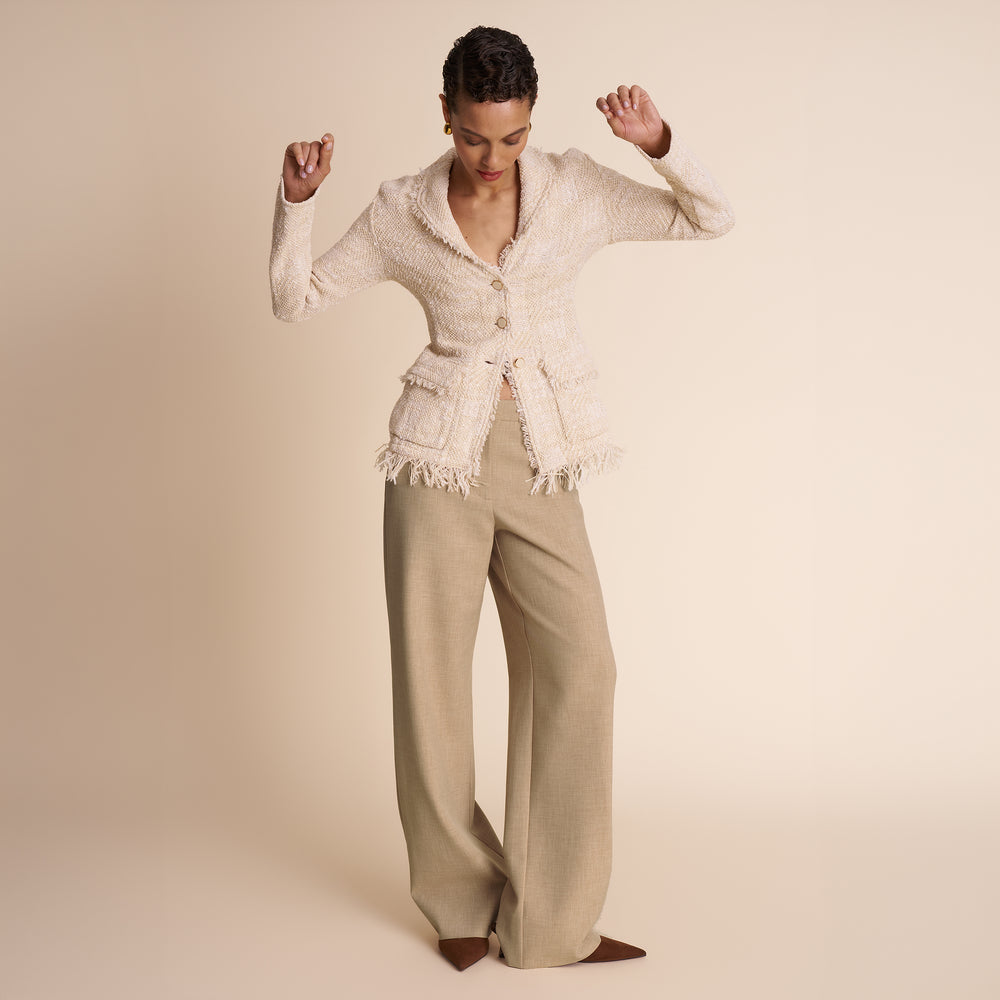 Woman wearing a beige outfit with a textured top and wide-leg pants on a beige background