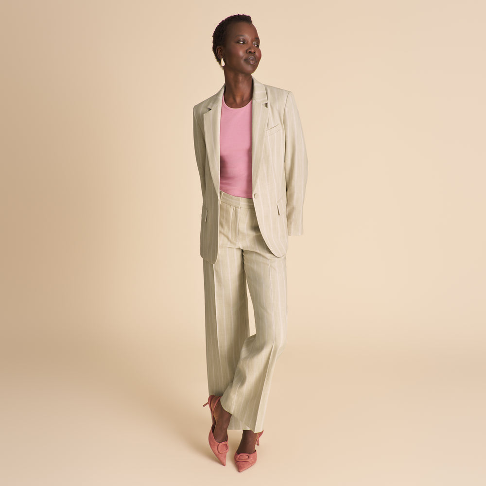Woman wearing a beige suit with a pink top on a beige background