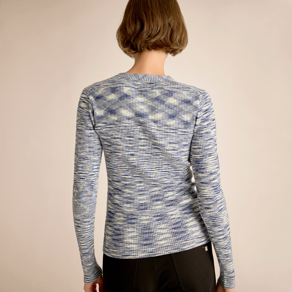 Person wearing a blue and white patterned long-sleeve shirt on a beige background