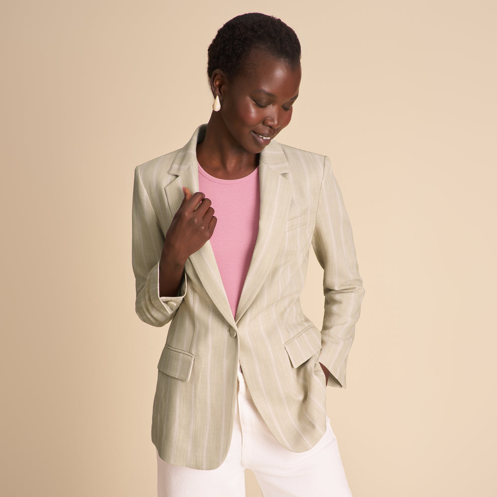 Woman wearing a beige blazer over a pink top on a beige background