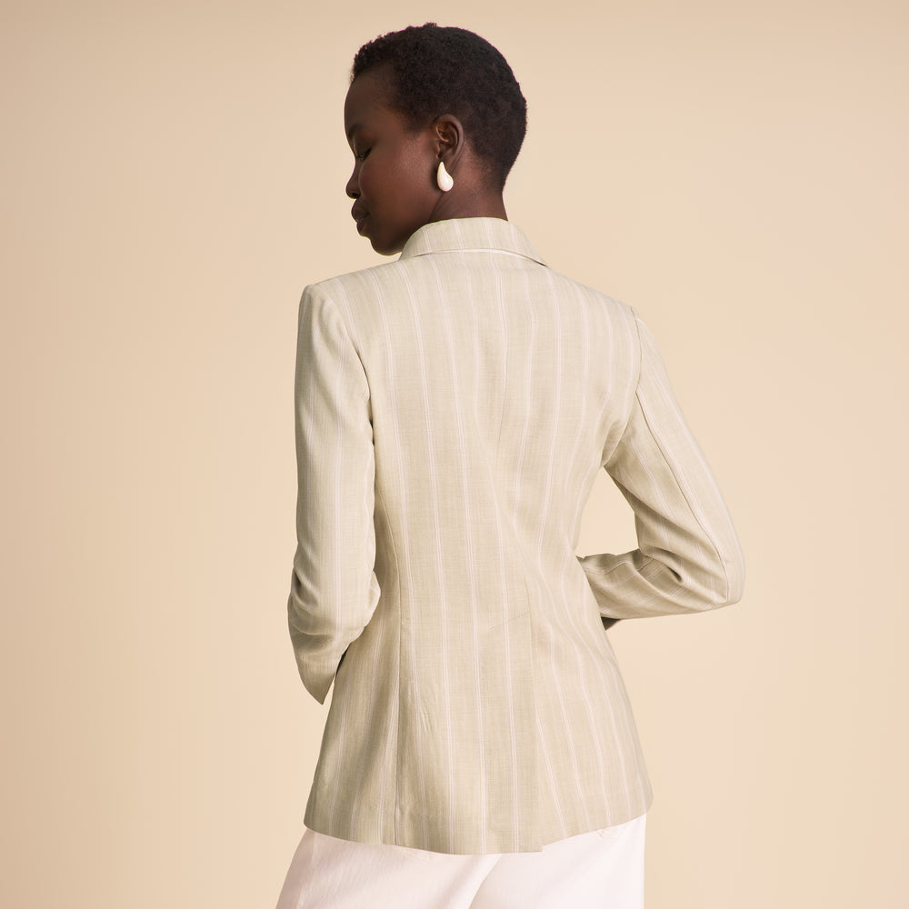 Person wearing a light-colored blazer against a beige background