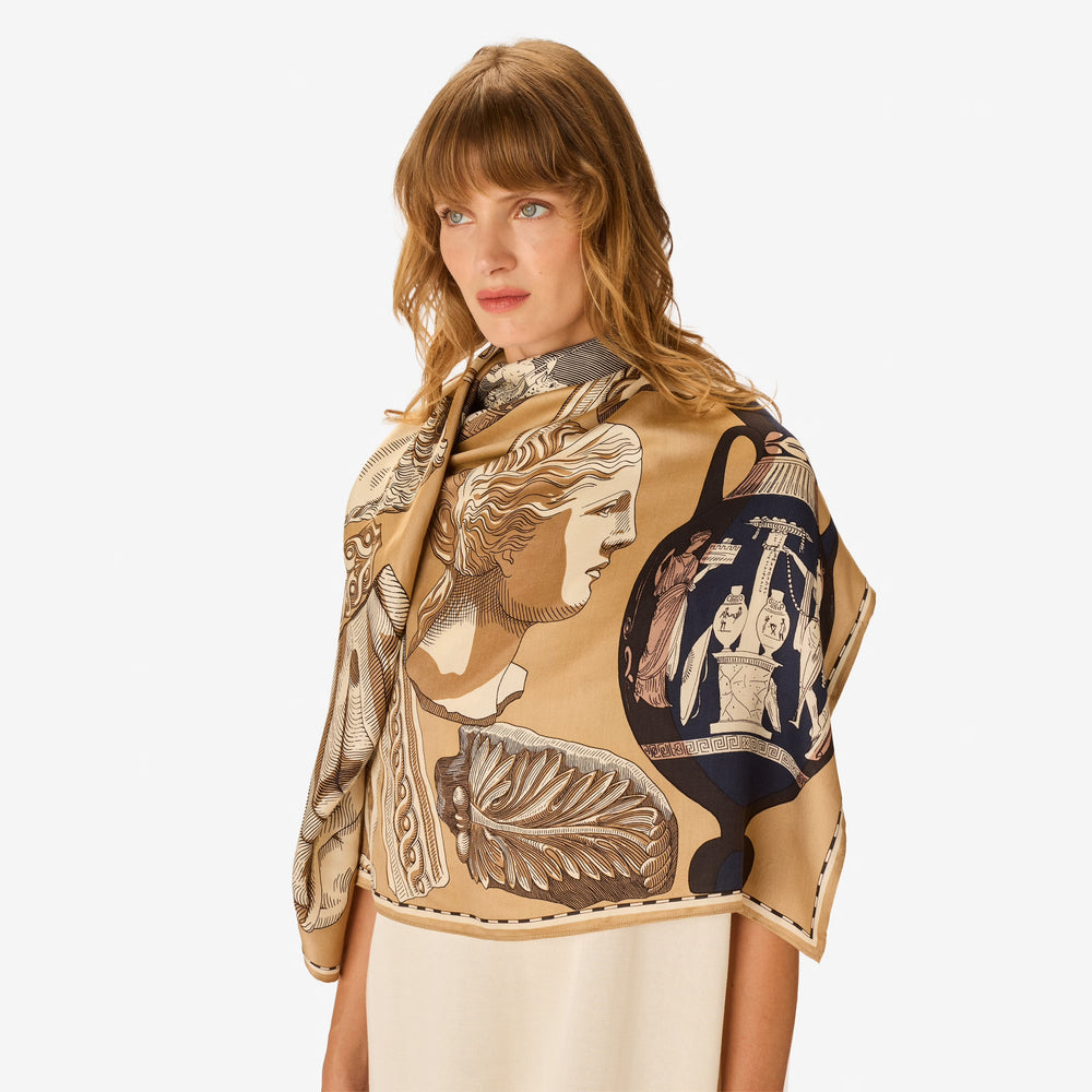 Woman wearing a decorative scarf with classical design on a plain background