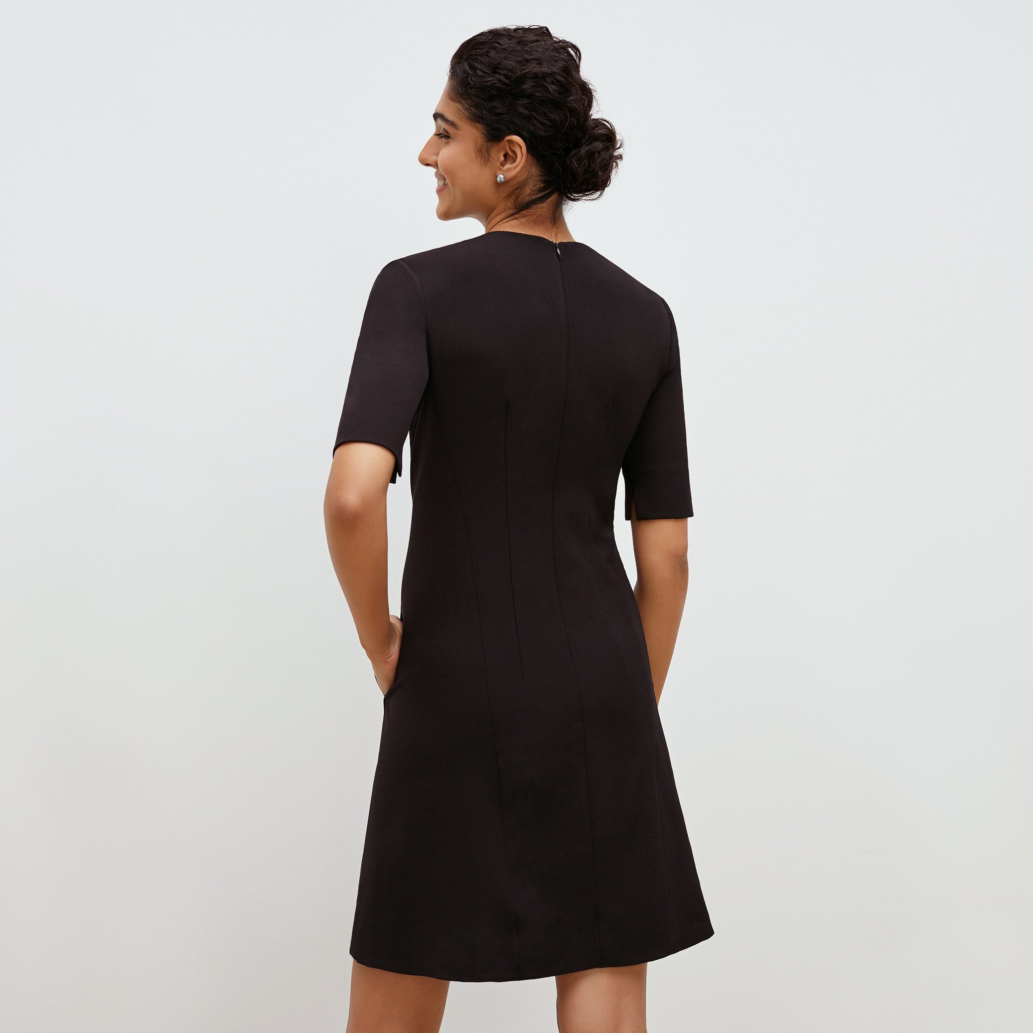 Back image of a woman standing wearing the emily dress in black