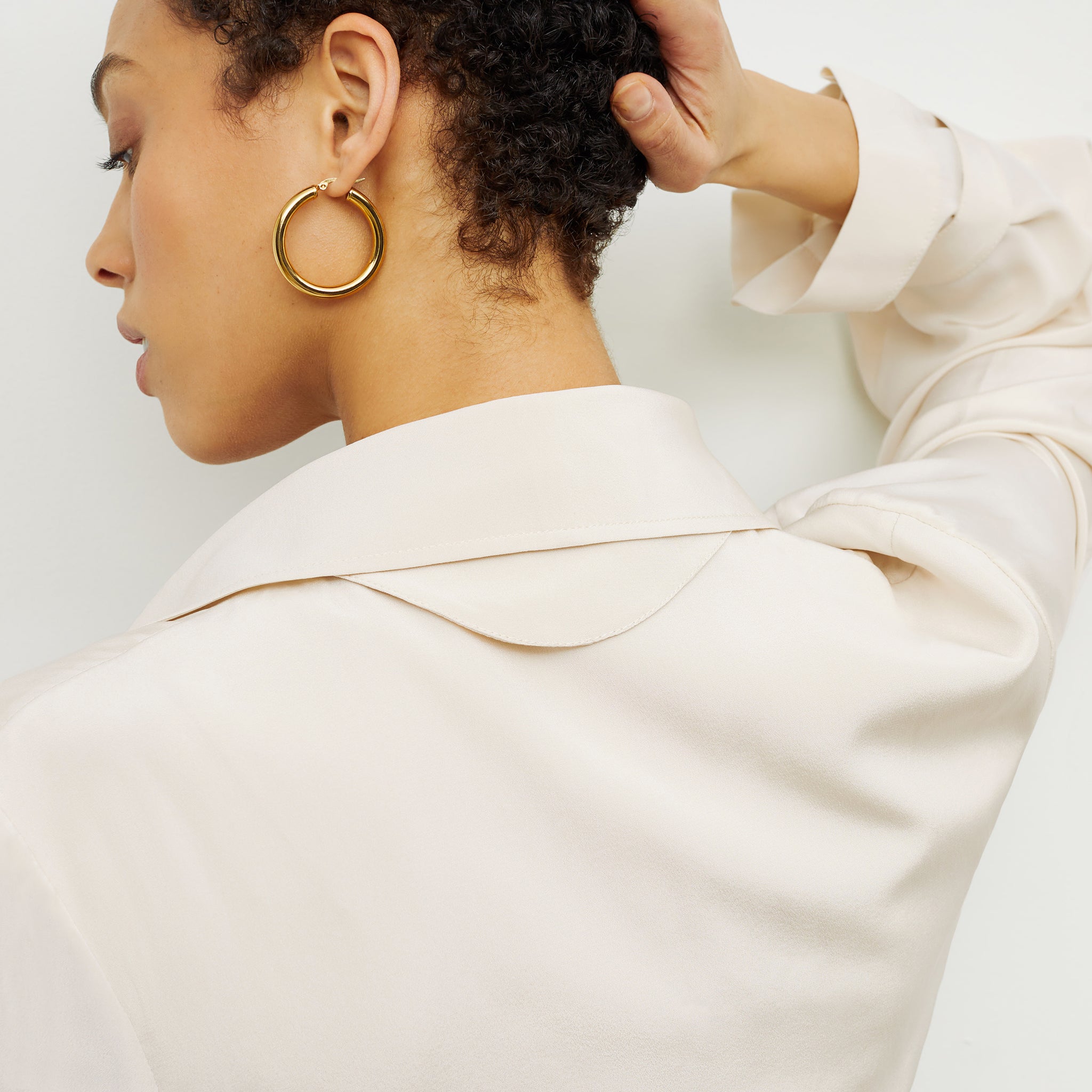 Detail image of a woman standing wearing the Claressa Earrings—Medium in Gold