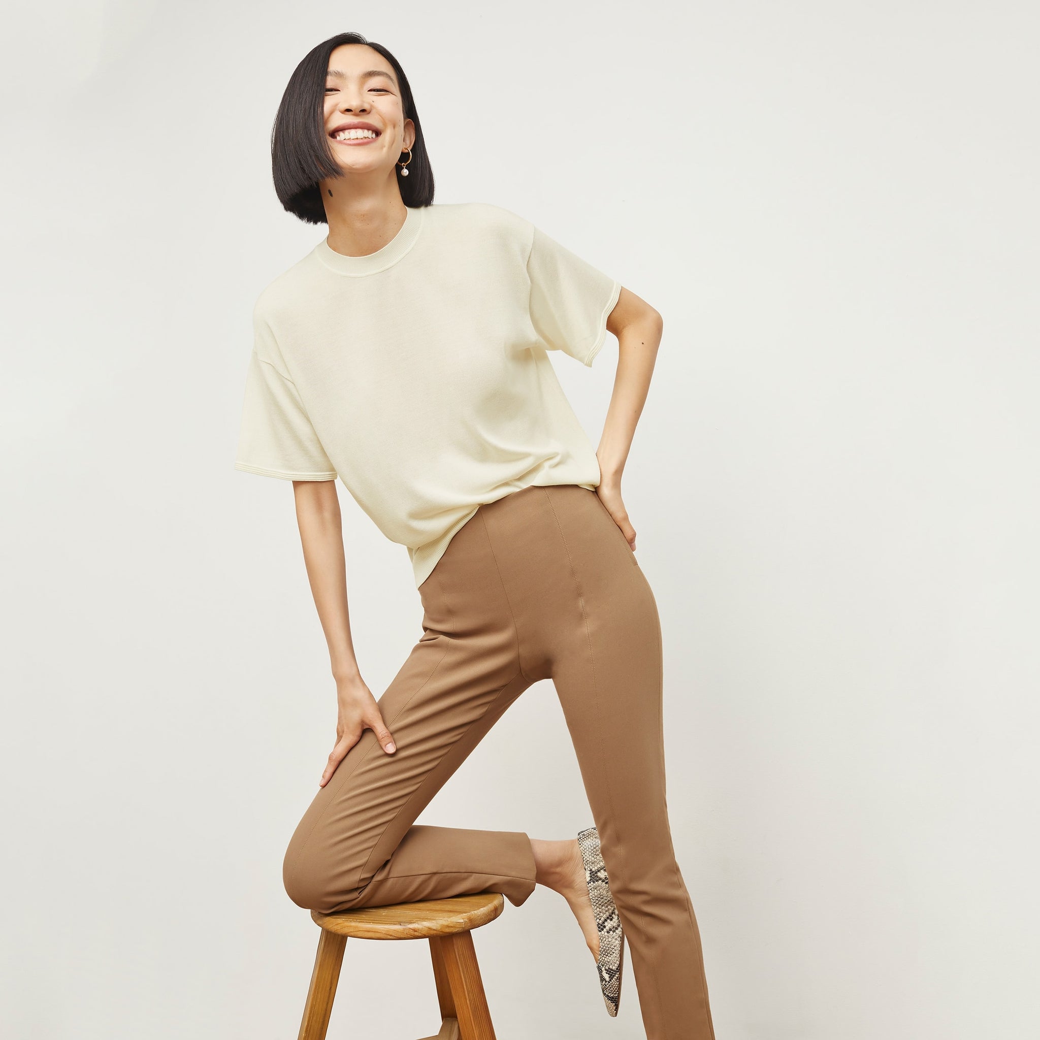 Front image of a woman sitting wearing the Foster Pant—Everstretch in Saddle 