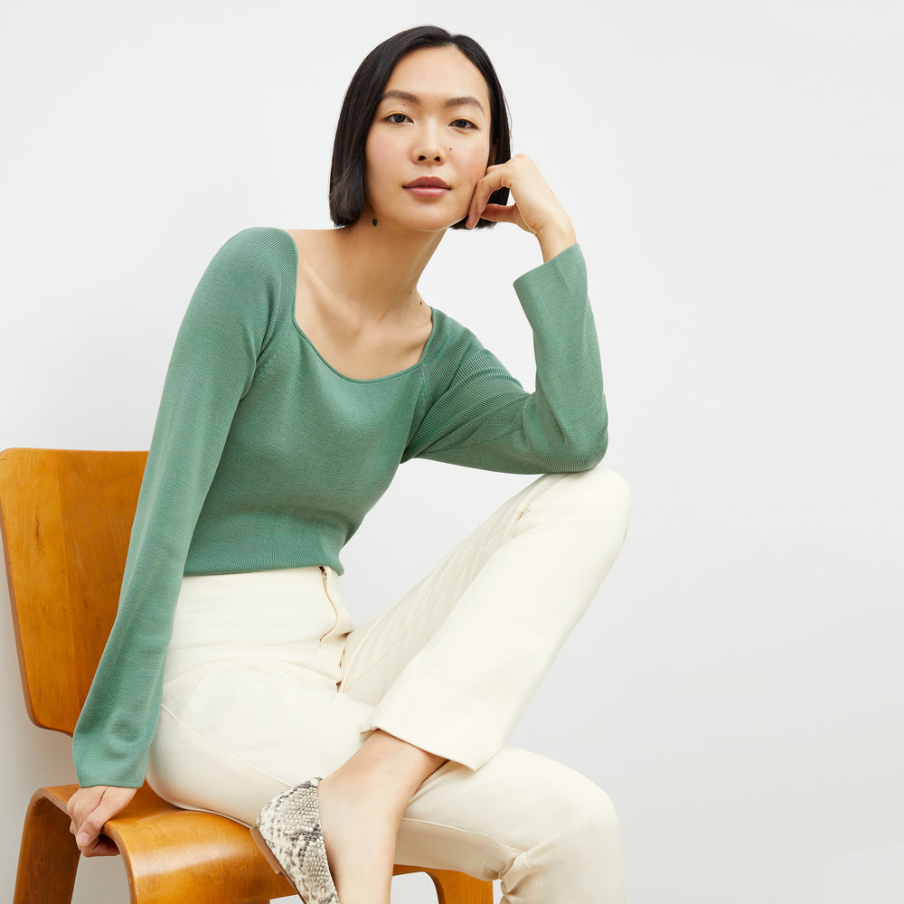Front image of a woman sitting wearing the joya top in spring green