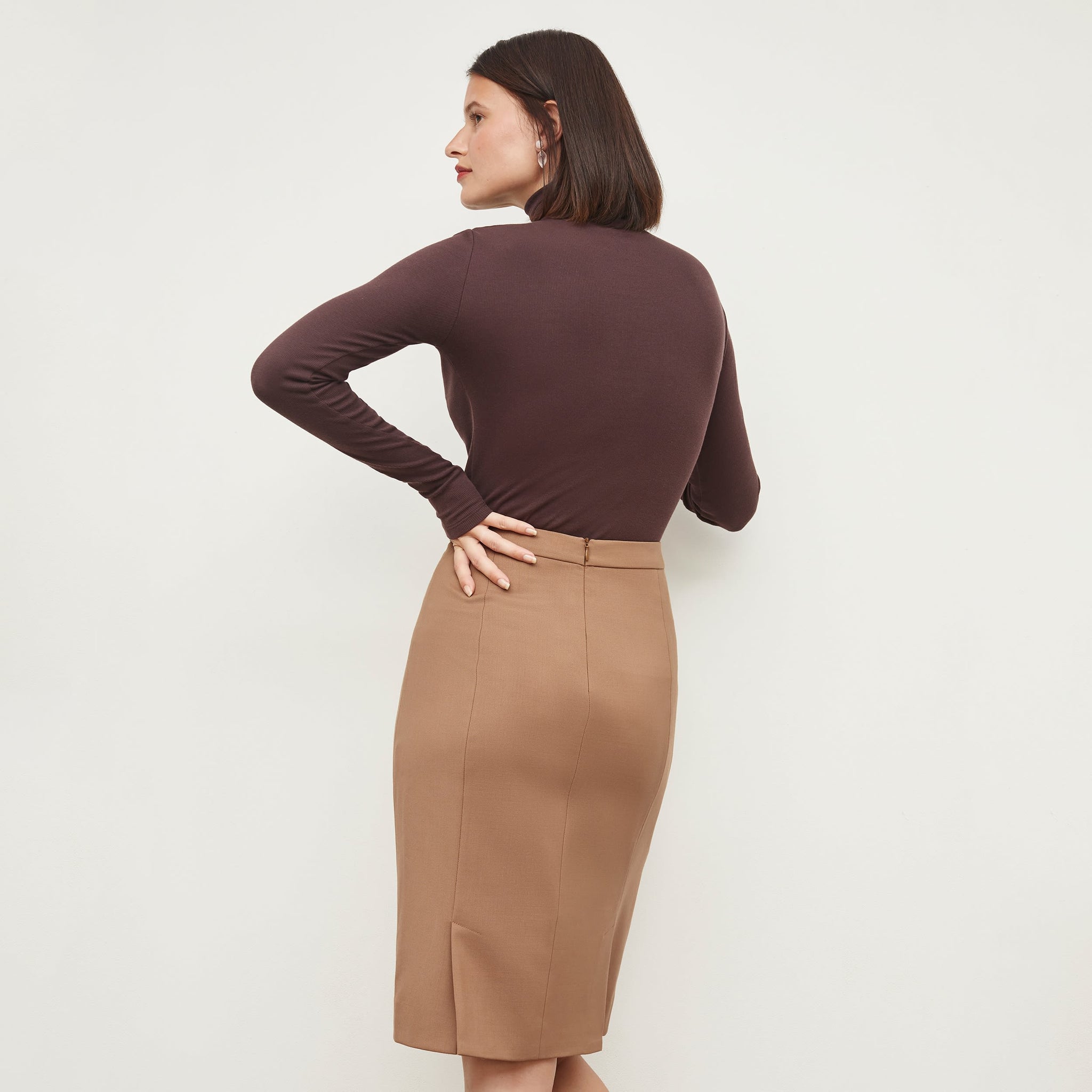 Back image of a woman standing wearing the Cobble Hill Skirt in Camel