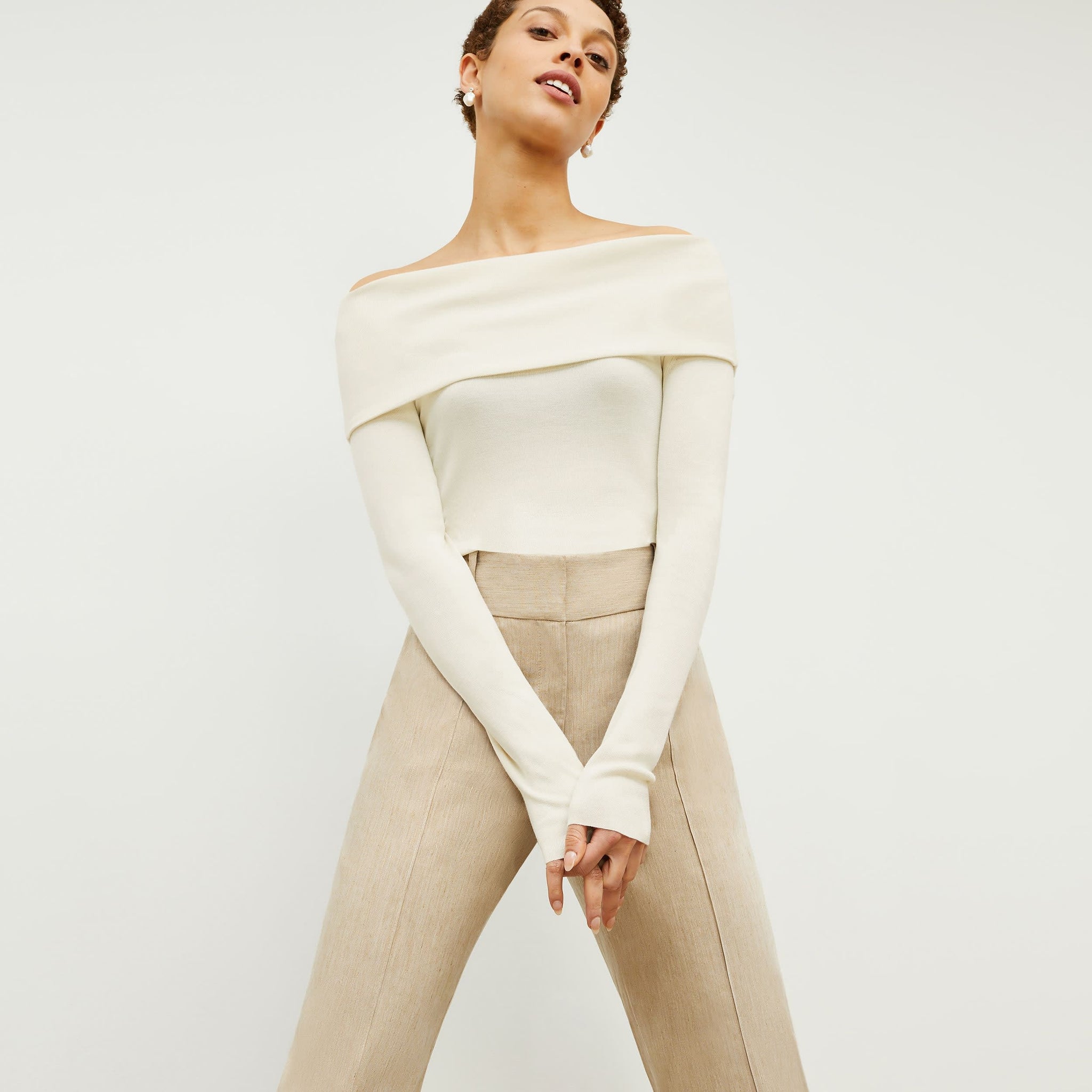 Front image of a woman standing wearing the dae top in cream