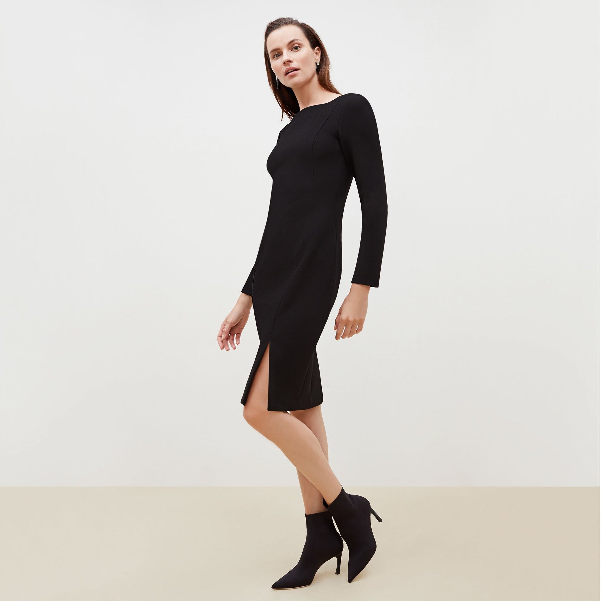 Side image of a woman standing wearing the Joanna Dress-Worth in Black