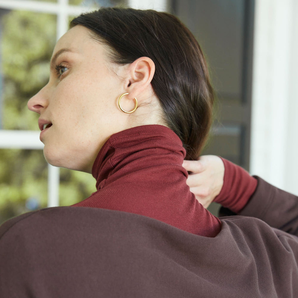 Front image of a woman standing wearing the Claressa Earrings in Gold