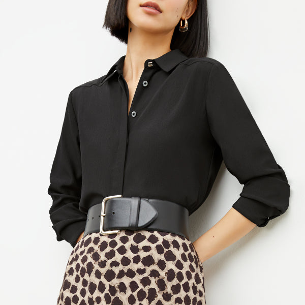 Image of a woman wearing a black button down with a leopard print skirt