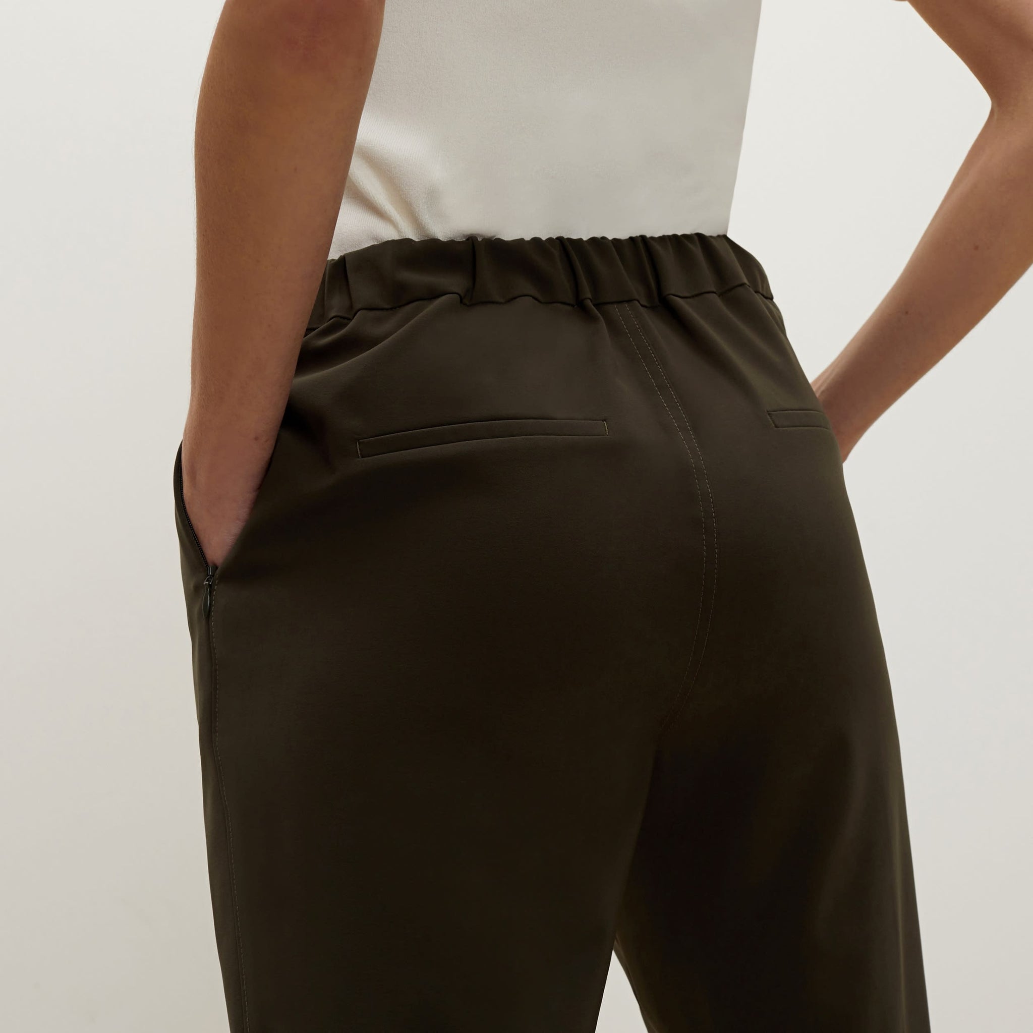 Back image of a woman standing wearing the colby pant in olive