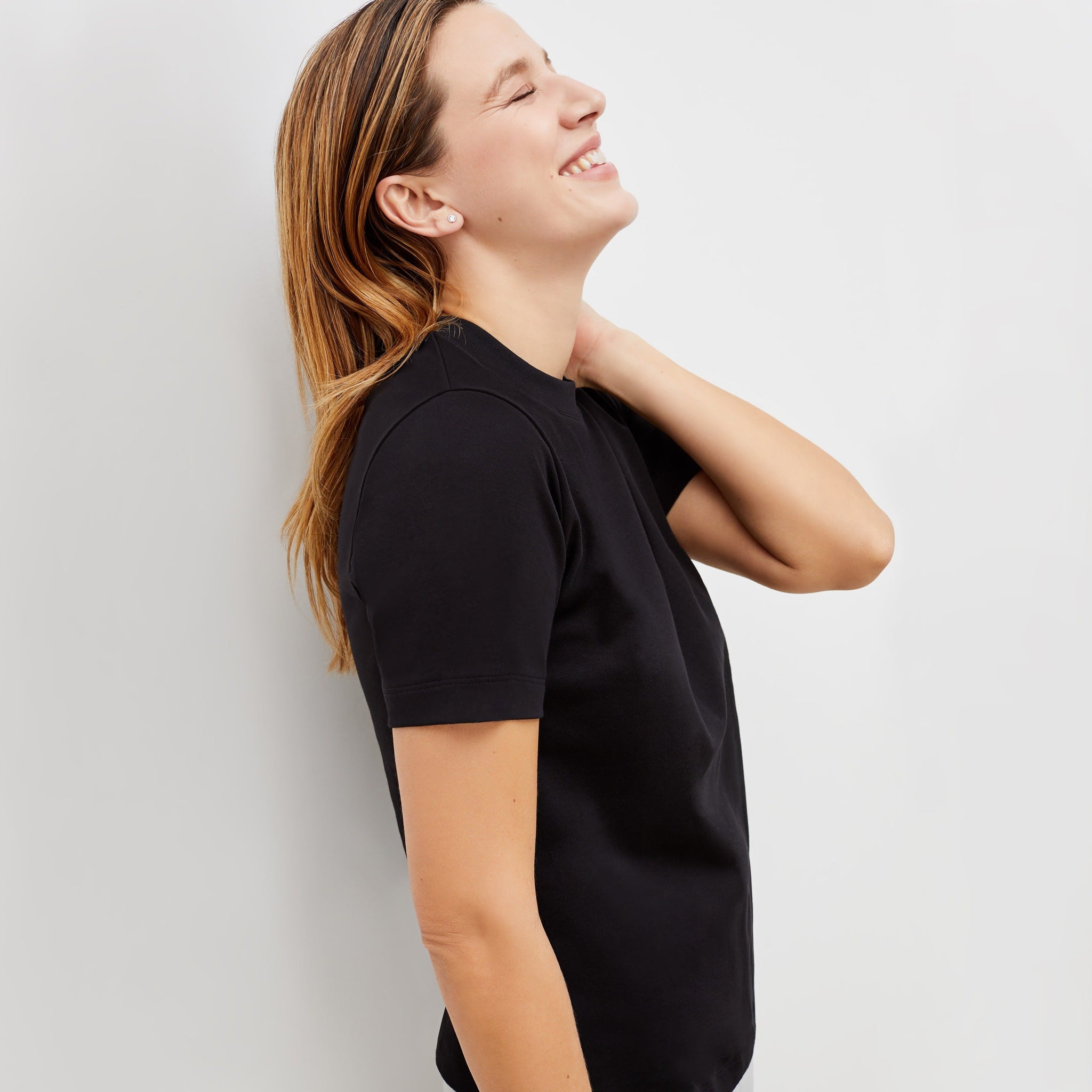 Side image of a woman standing wearing the leslie top in compact cotton in black