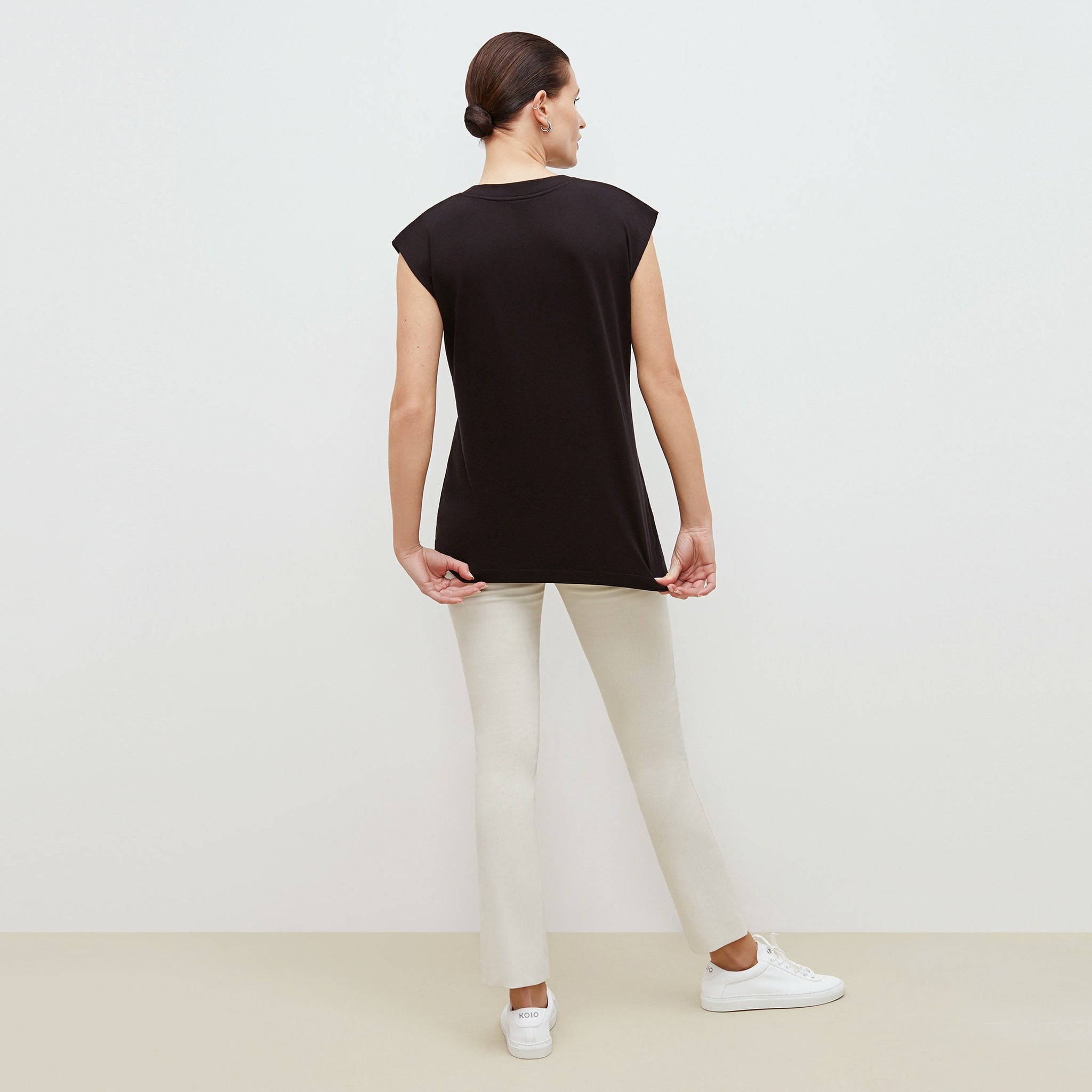 Back image of a woman standing wearing the alina top in compact cotton in black