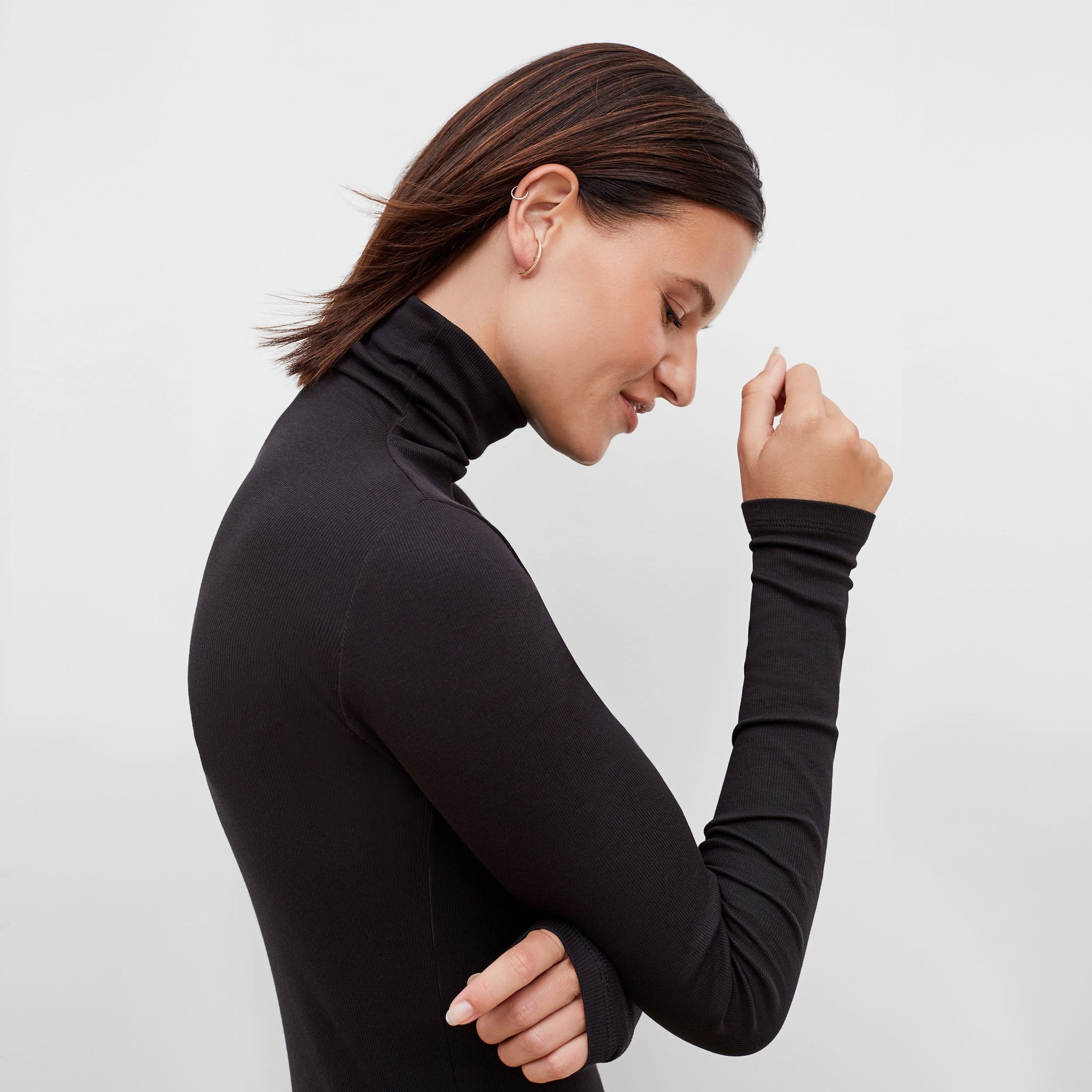 Side image of a woman standing wearing the axam top in black