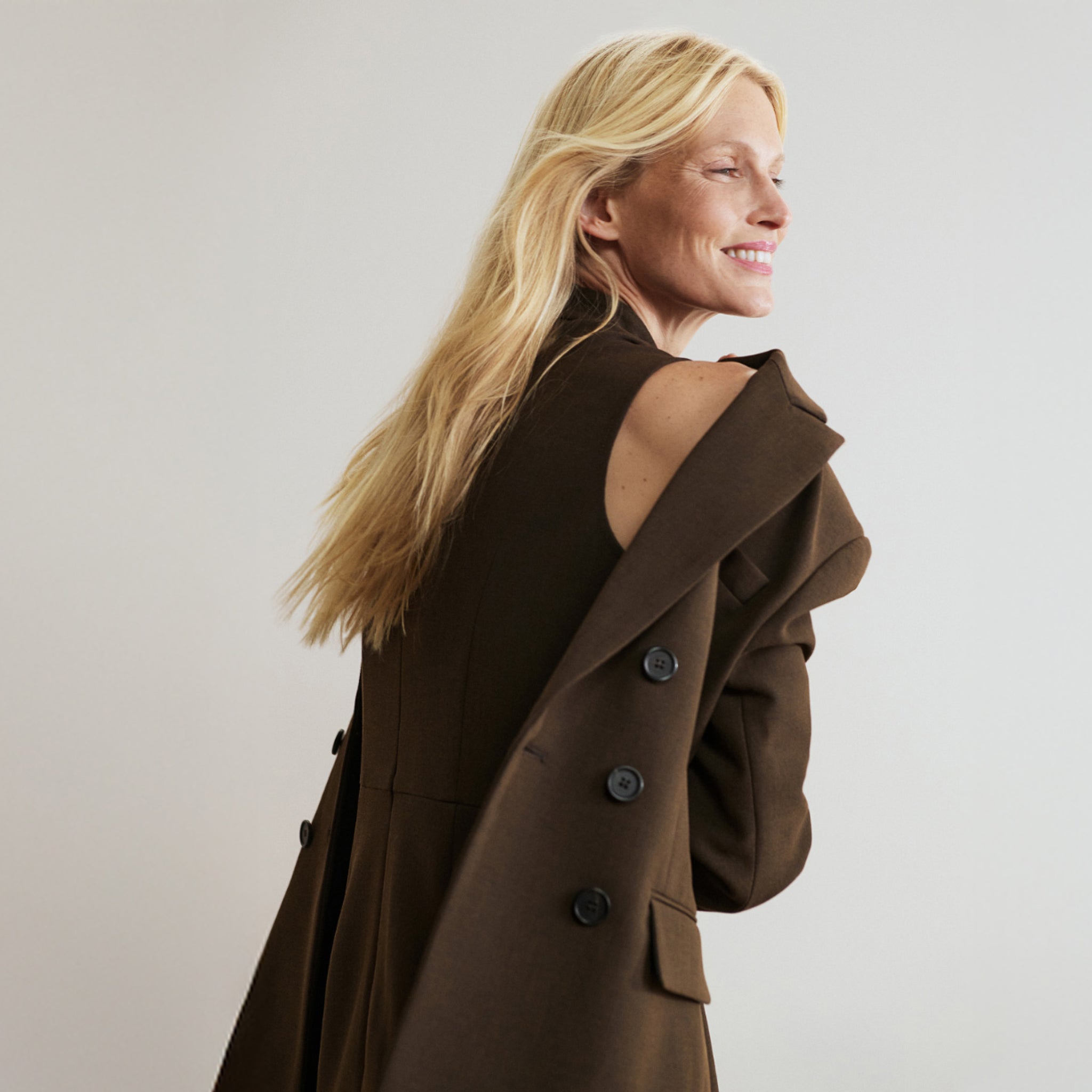Woman wearing a brown coat against a plain background