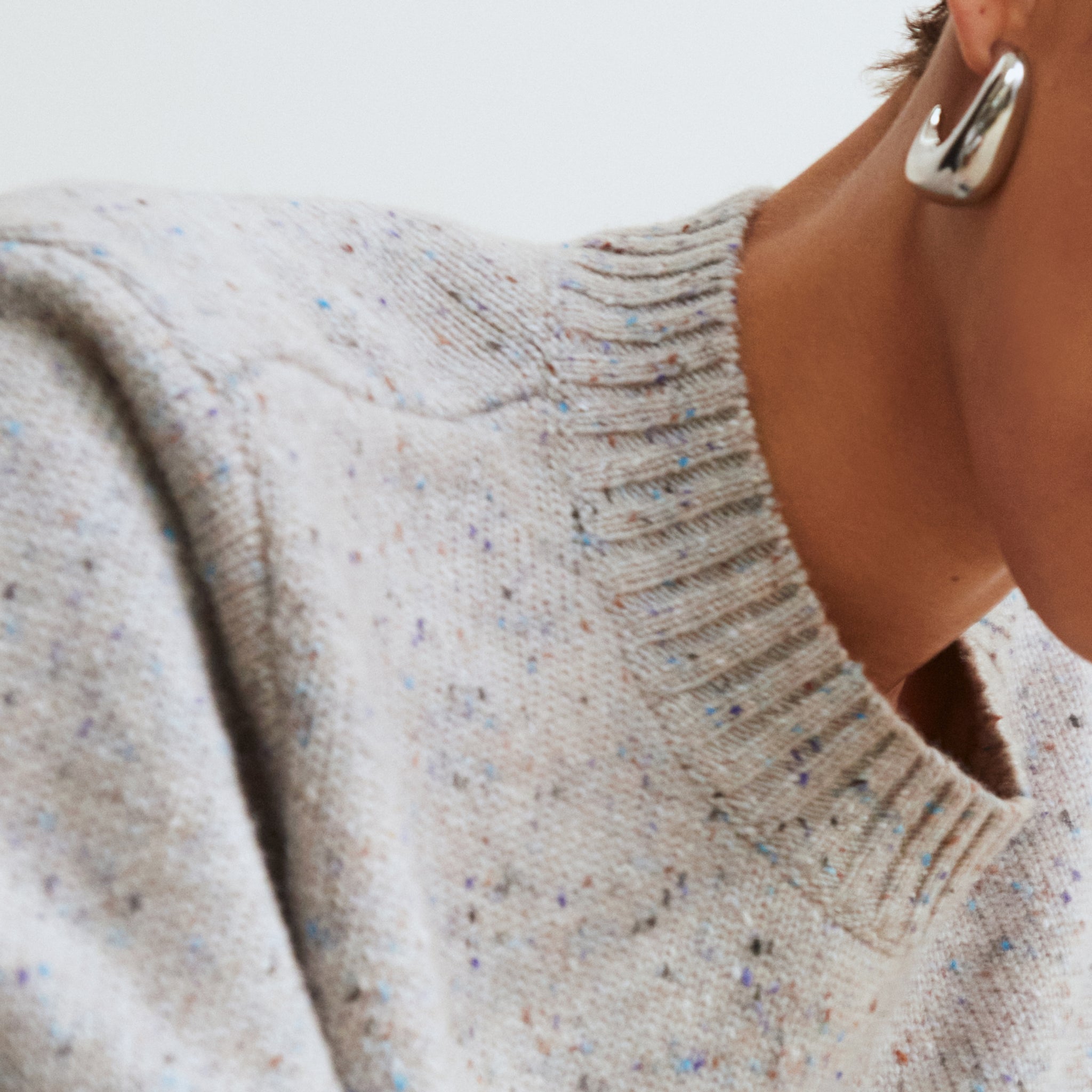 Close-up of a person wearing a textured sweater with a blurred background