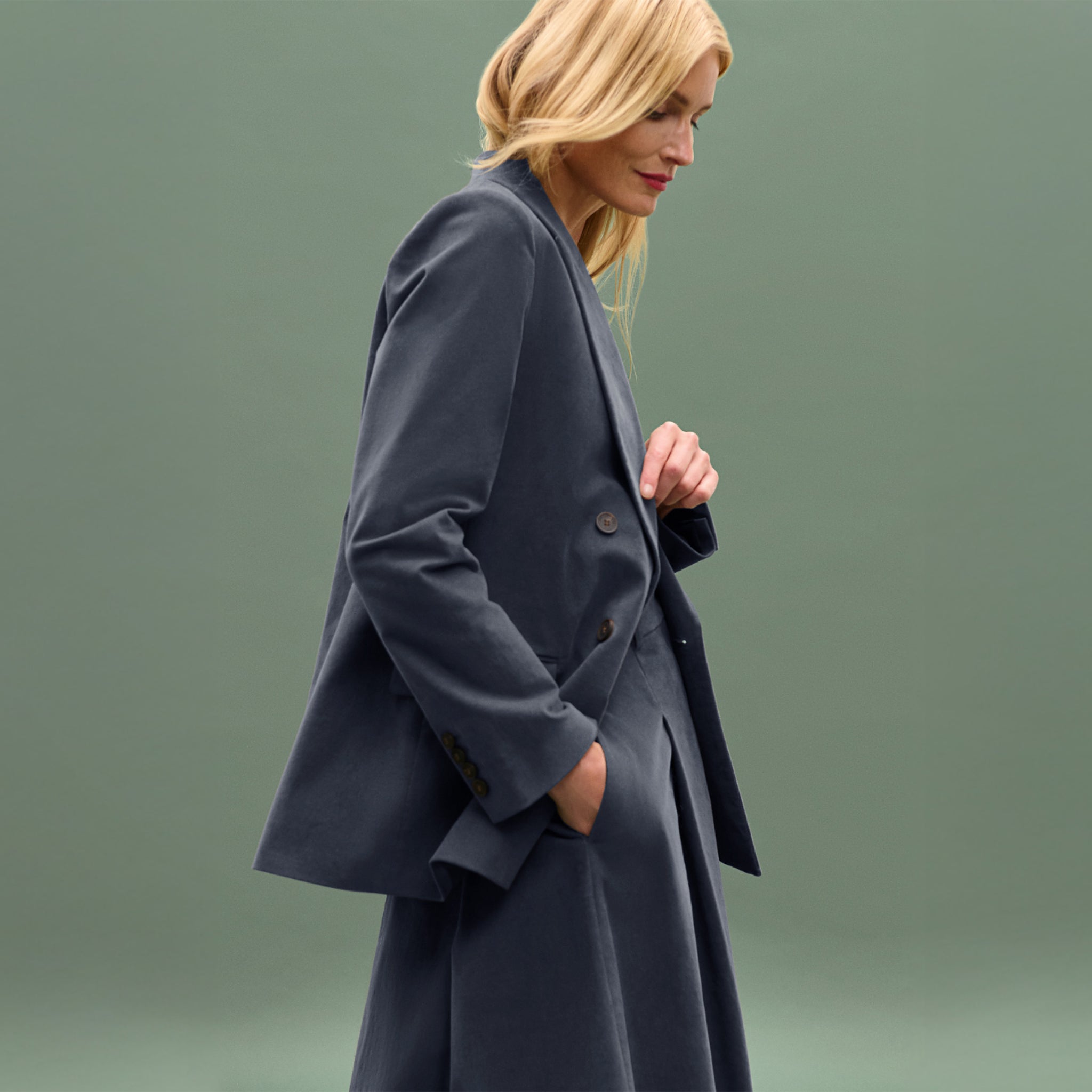 Woman wearing a dark gray coat against a green background