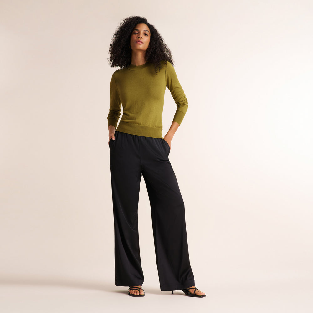 Woman wearing an olive green color long sleeve sweater with black wide leg pants