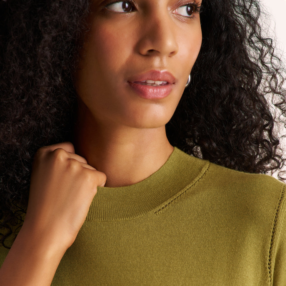 Woman wearing an olive green color long sleeve sweater with black wide leg pants