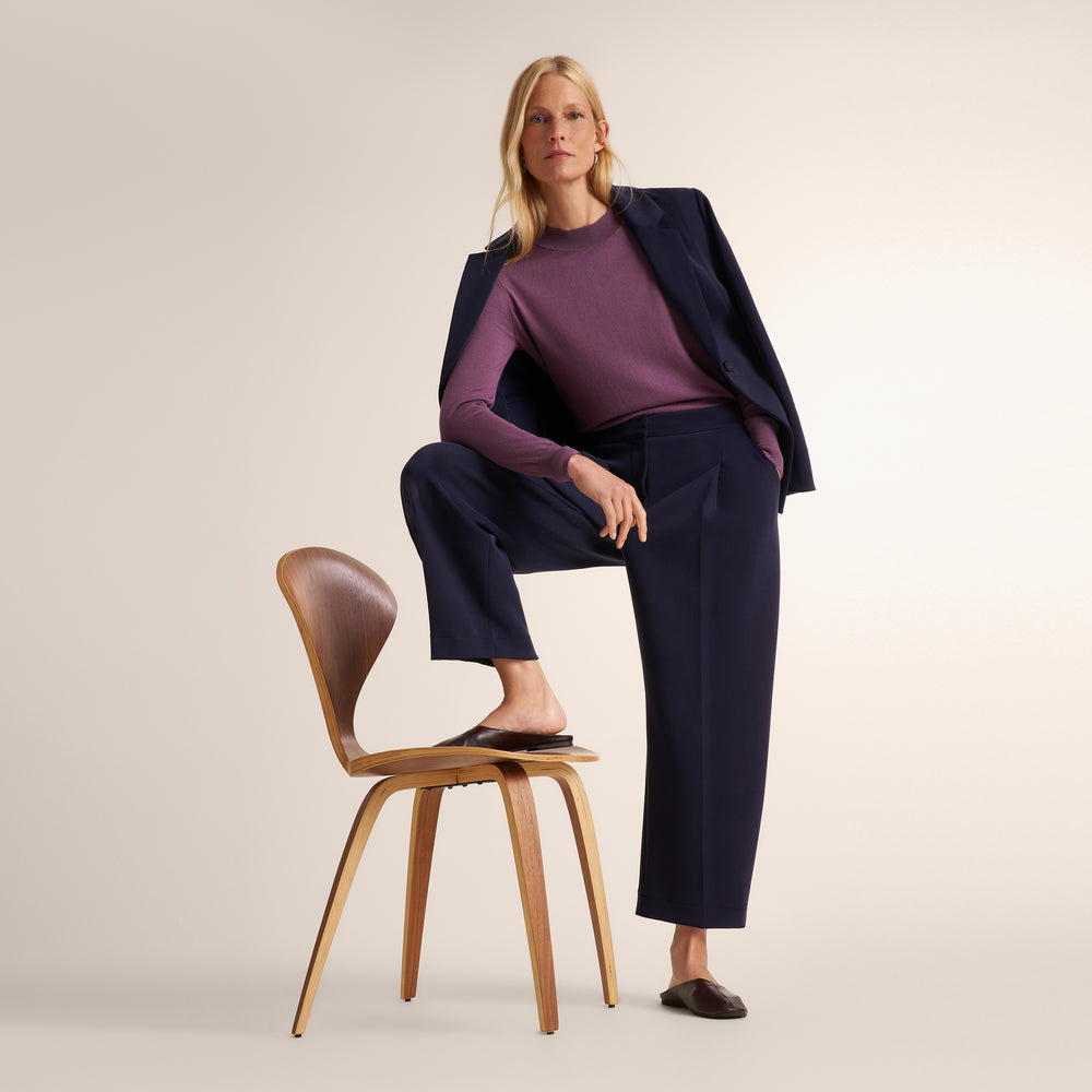 Woman wearing a purple fig color long sleeve sweater with navy wide leg pants